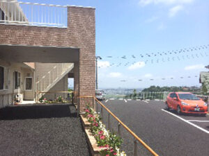 施設の外観。赤レンガの建物と駐車場、周辺道路が見える